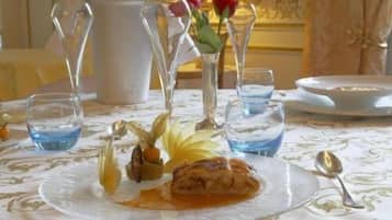A dining table with a plate of food, a pitcher, and several glasses of water.