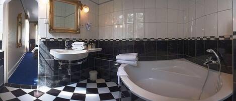 Un baño con piso a cuadros, un lavamanos, un espejo y una bañera.