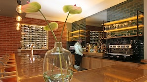 Un coin bar avec un vase en verre transparent, un mur en briques et des étagères remplies de bouteilles et de verres.