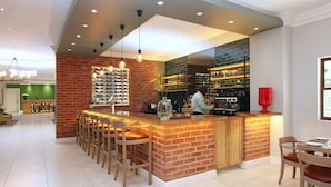 Une cuisine moderne avec un mur d’accent en briques, un coin bar avec des tabourets et un grand îlot central.