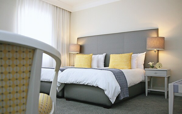 A hotel room with a bed, two bedside tables, a chair, and a lamp.