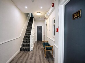 A hallway with a staircase, a bench, and a door marked 'B03'. - Hyde Park Court Hotel (London)