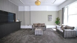Een moderne woonkamer met een grijze bank, een salontafel en een vloerkleed met een patroon.
