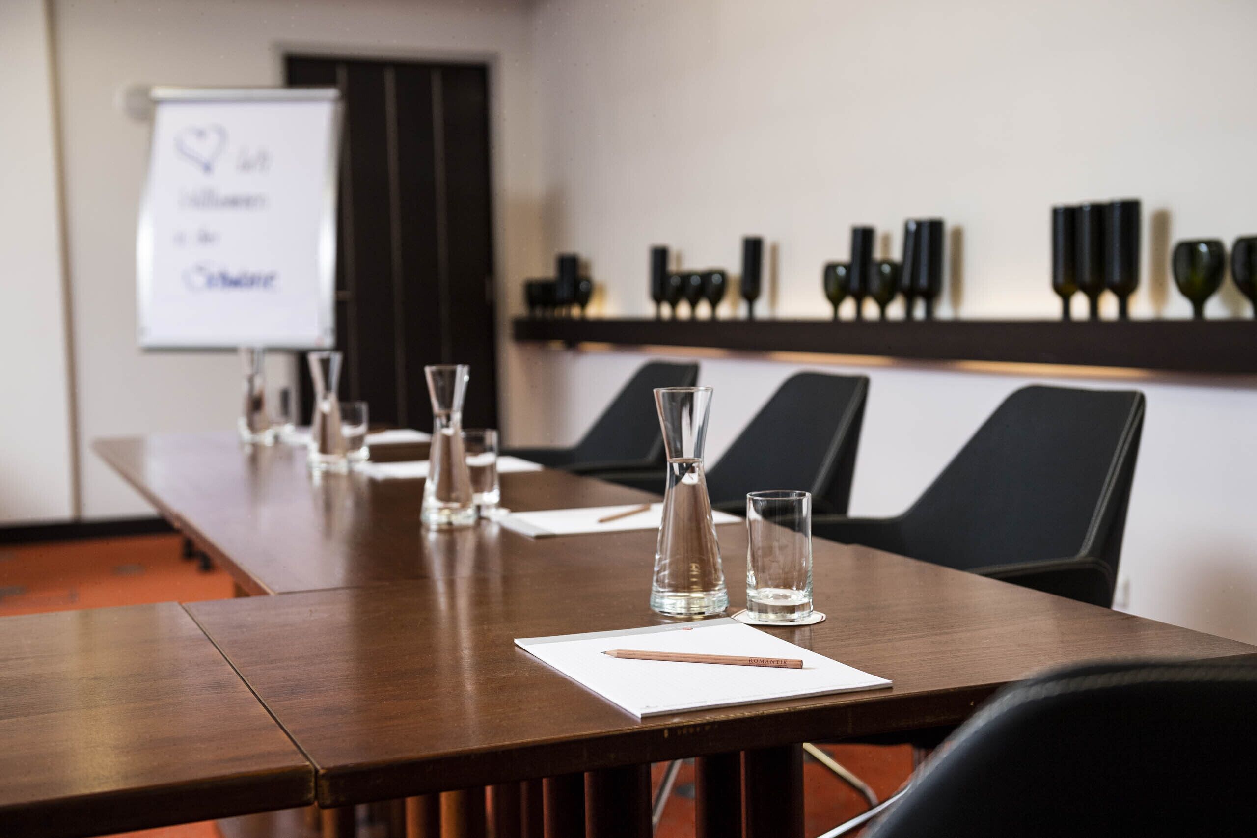 A conference room with a long table, chairs, a whiteboard, and decorative vases.