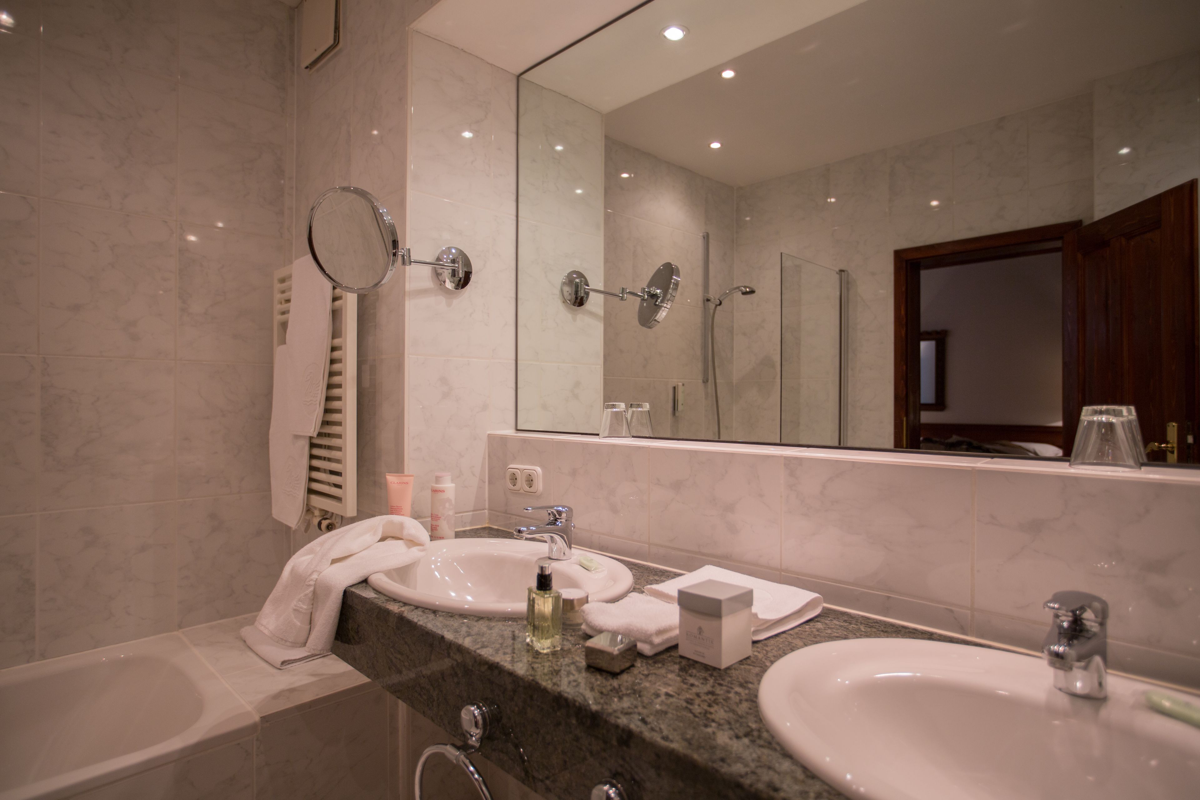 A modern bathroom with a marble sink, a large mirror, and a bathtub.