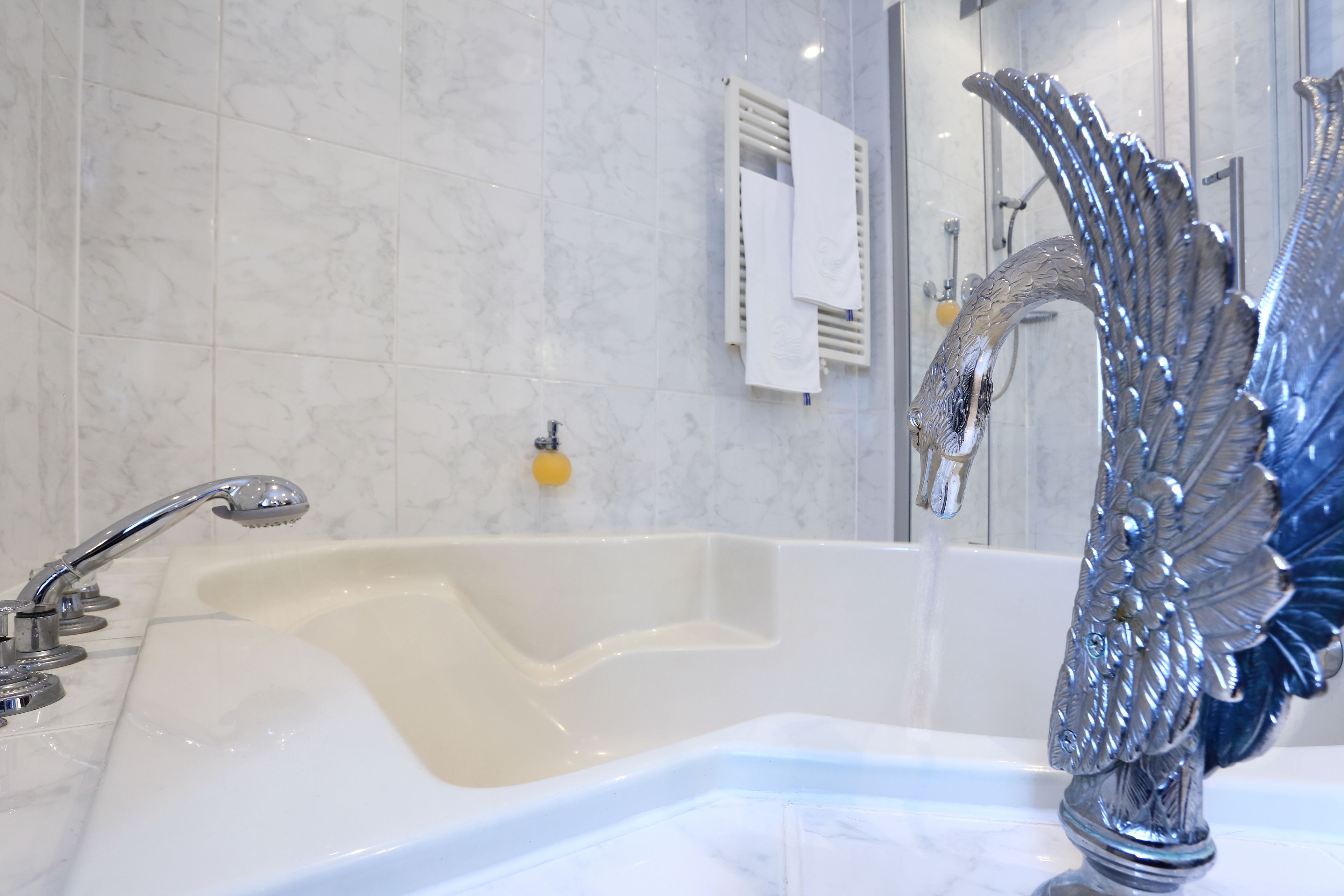 Un baño con una bañera grande, una llave moderna y un cabezal de ducha decorativo.