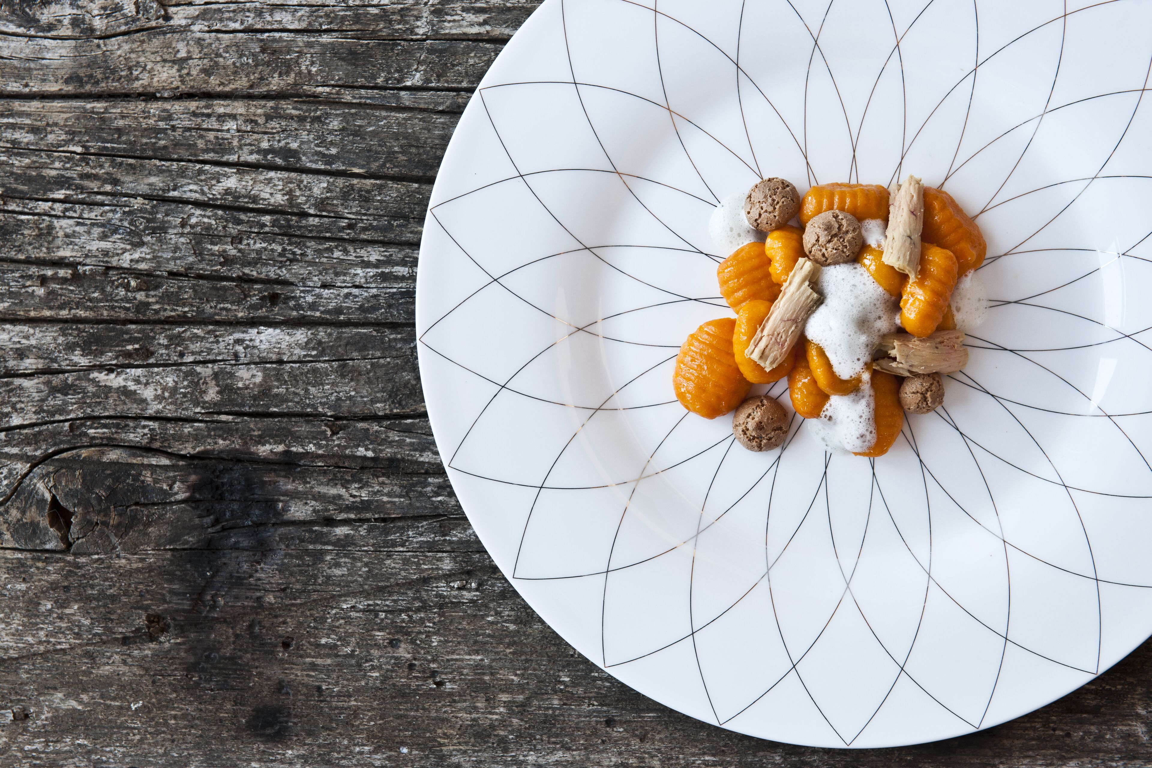 Un plato blanco con un diseño geométrico, sobre una superficie de madera rústica.