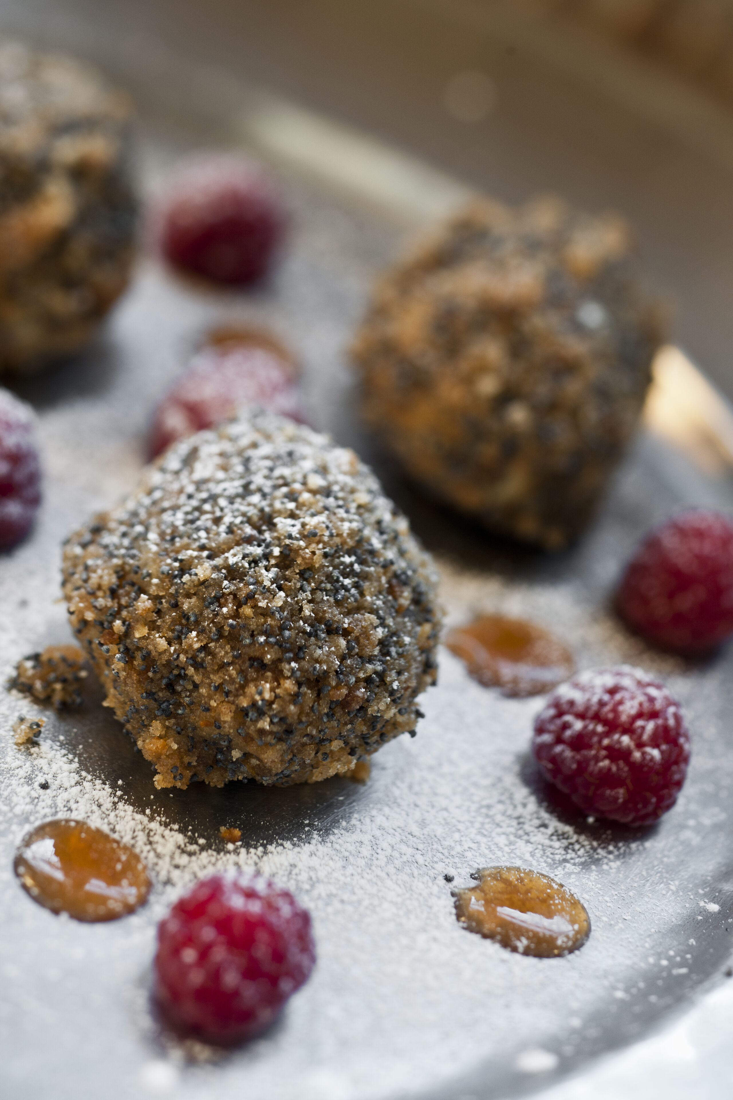 A dessert plate with round, textured balls and scattered raspberries.