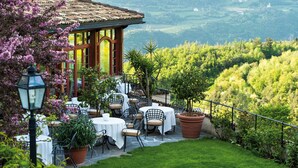 A restaurant with outdoor seating overlooking a scenic valley. - Romantik Hotel Turm (Fie allo Sciliar)