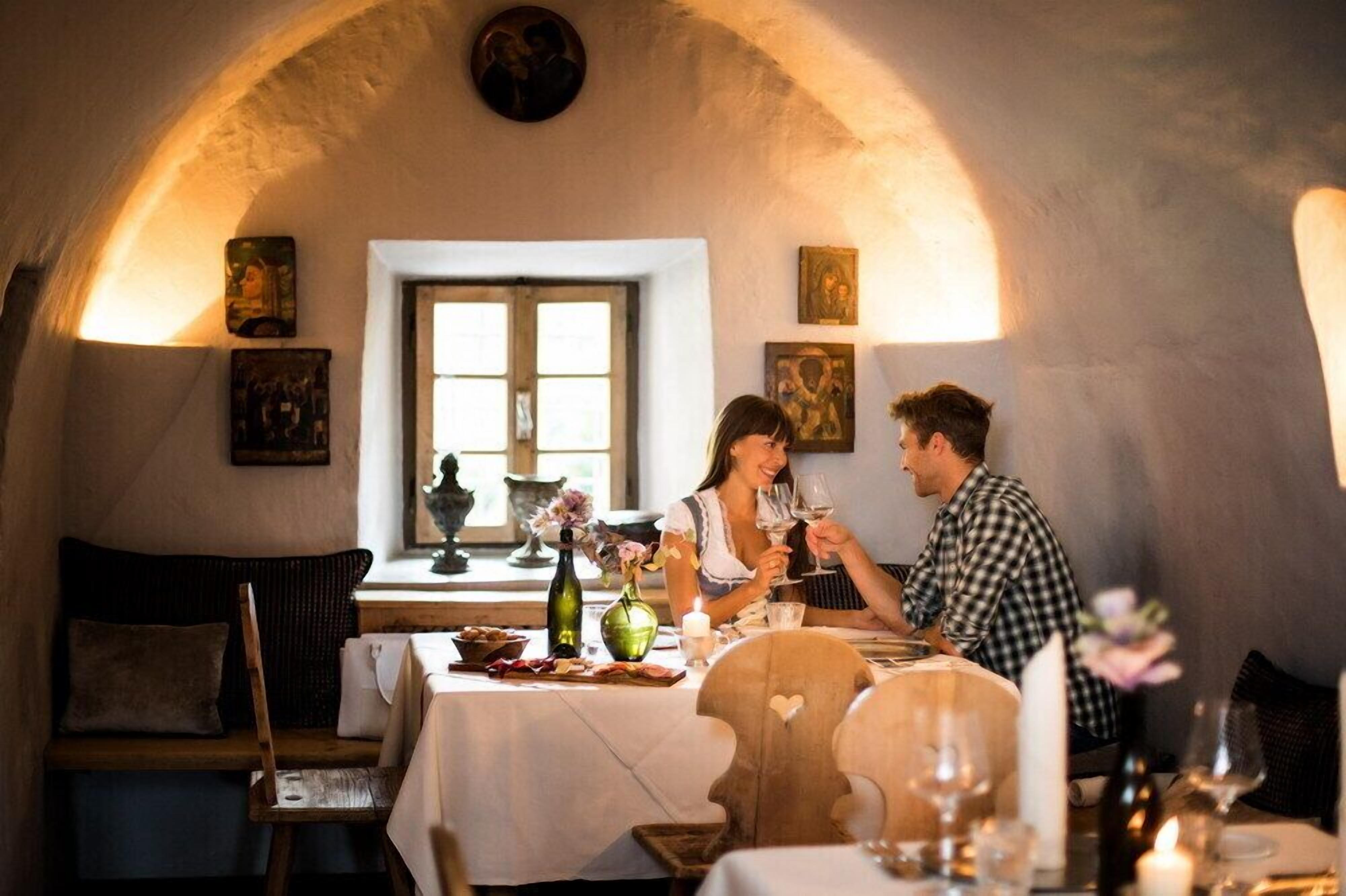 Un coin repas chaleureux, agrémenté d’une arche en pierre rustique, de meubles en bois et d’œuvres d’art accrochées aux murs.