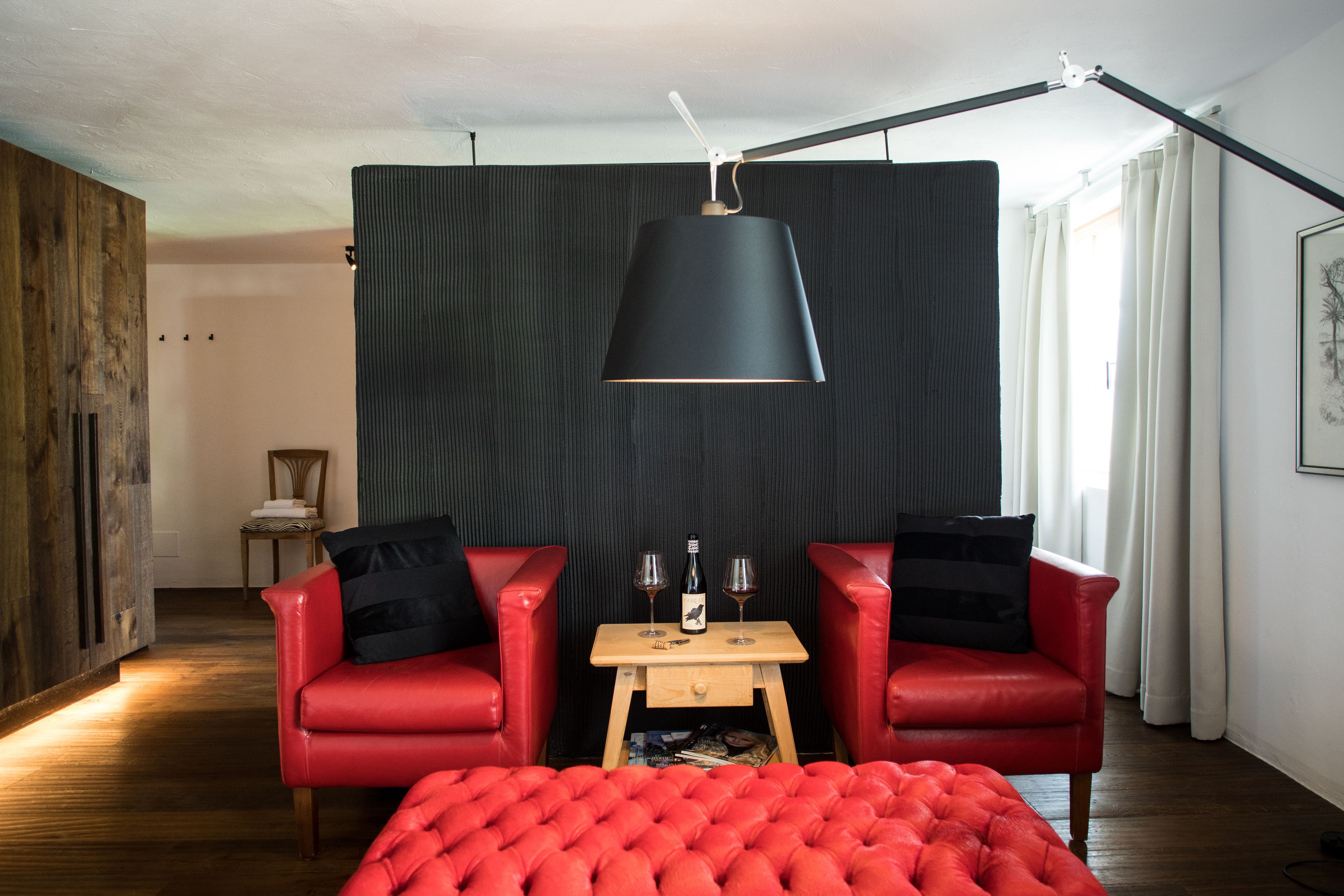 Una sala de estar moderna con un sofá rojo, una mesa de centro de madera y una lámpara colgante negra.