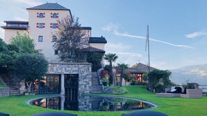 A courtyard with a pool, outdoor seating, and a building with a stone facade and multiple windows. - Romantik Hotel Turm (Fie allo Sciliar)