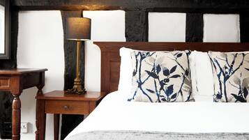 A bedroom with a wooden headboard, a bedside table with a lamp, and a bed with patterned pillows.