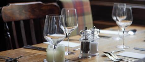 A dining table set with wine glasses, a candle, salt and pepper shakers, and cutlery.