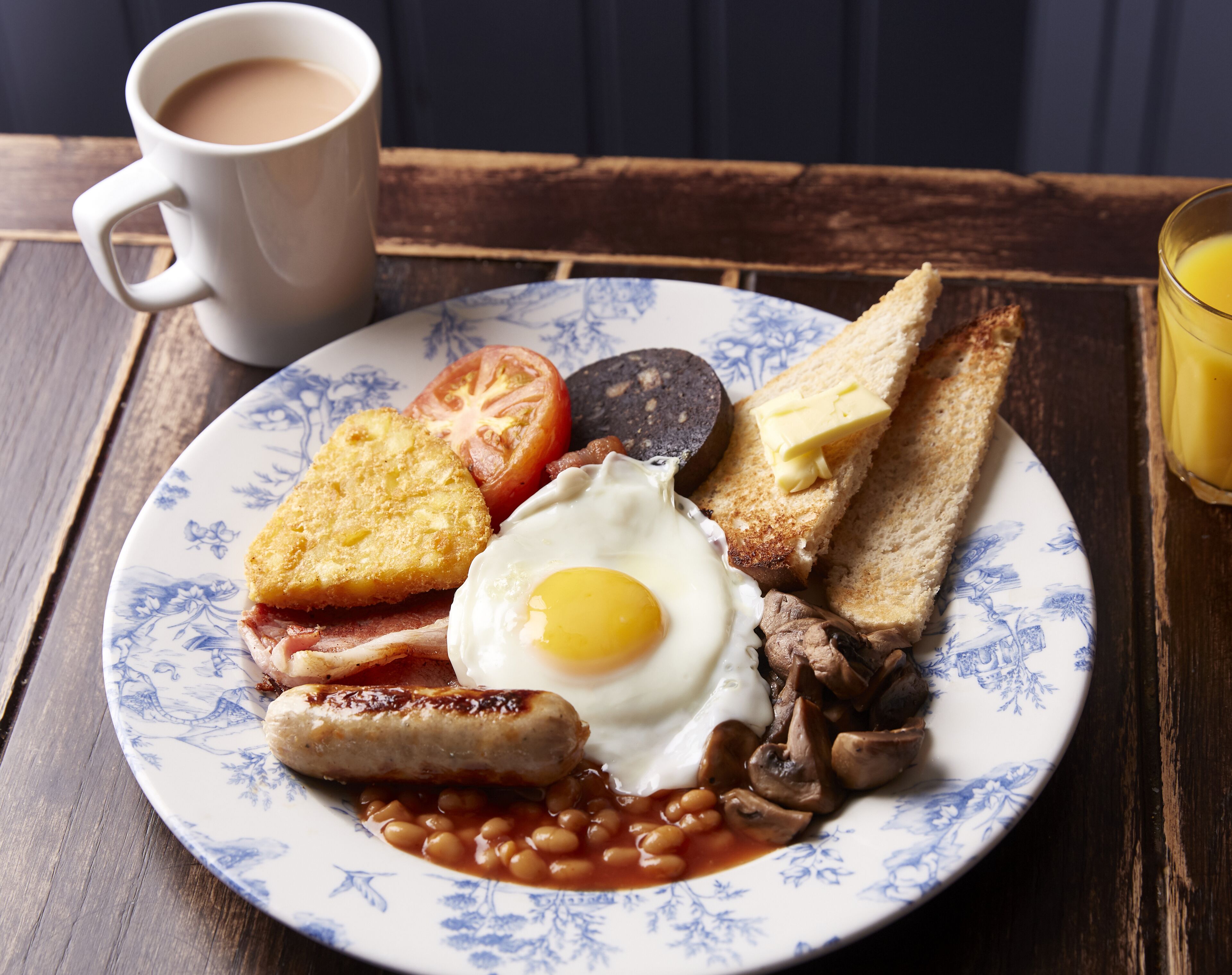A plate of breakfast food including toast, eggs, sausages, beans, and tomatoes.