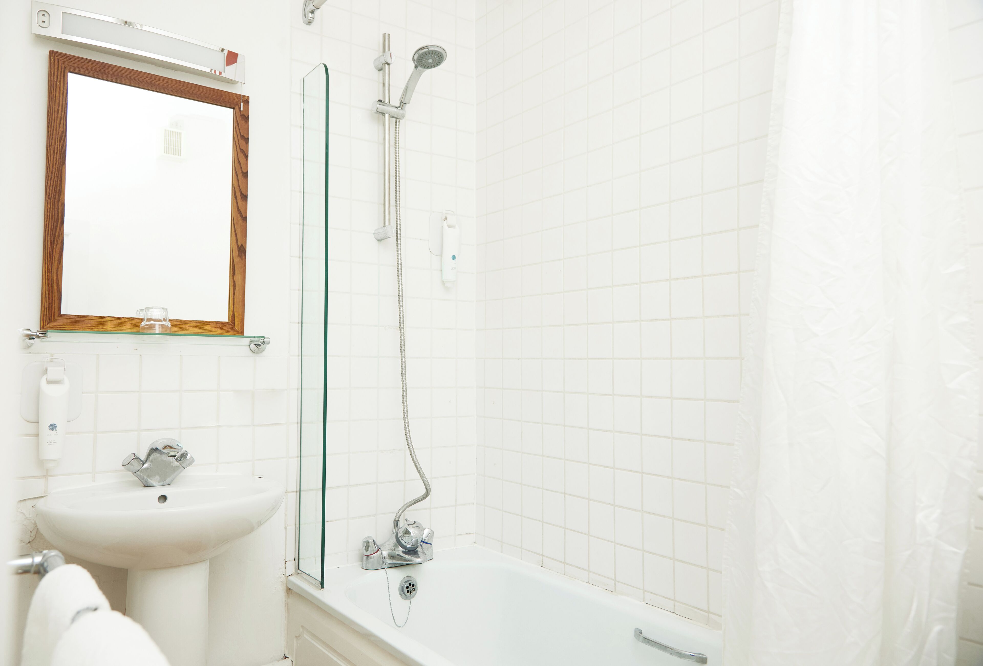 A bathroom with a sink, mirror, and shower.