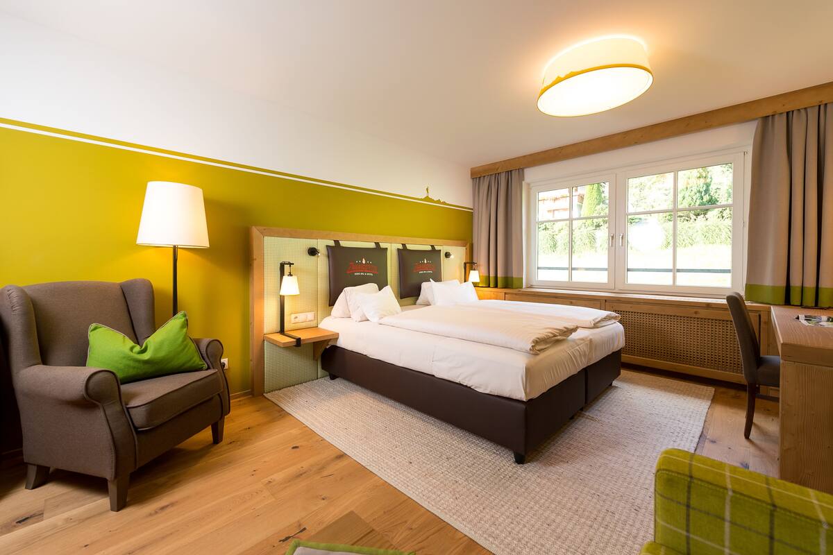 Een hotelkamer met een bed, een bureau, een stoel, een lamp en een raam.