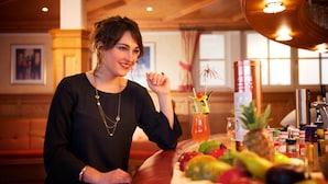 Une personne assise à une table, devant une variété de fruits et une boisson.