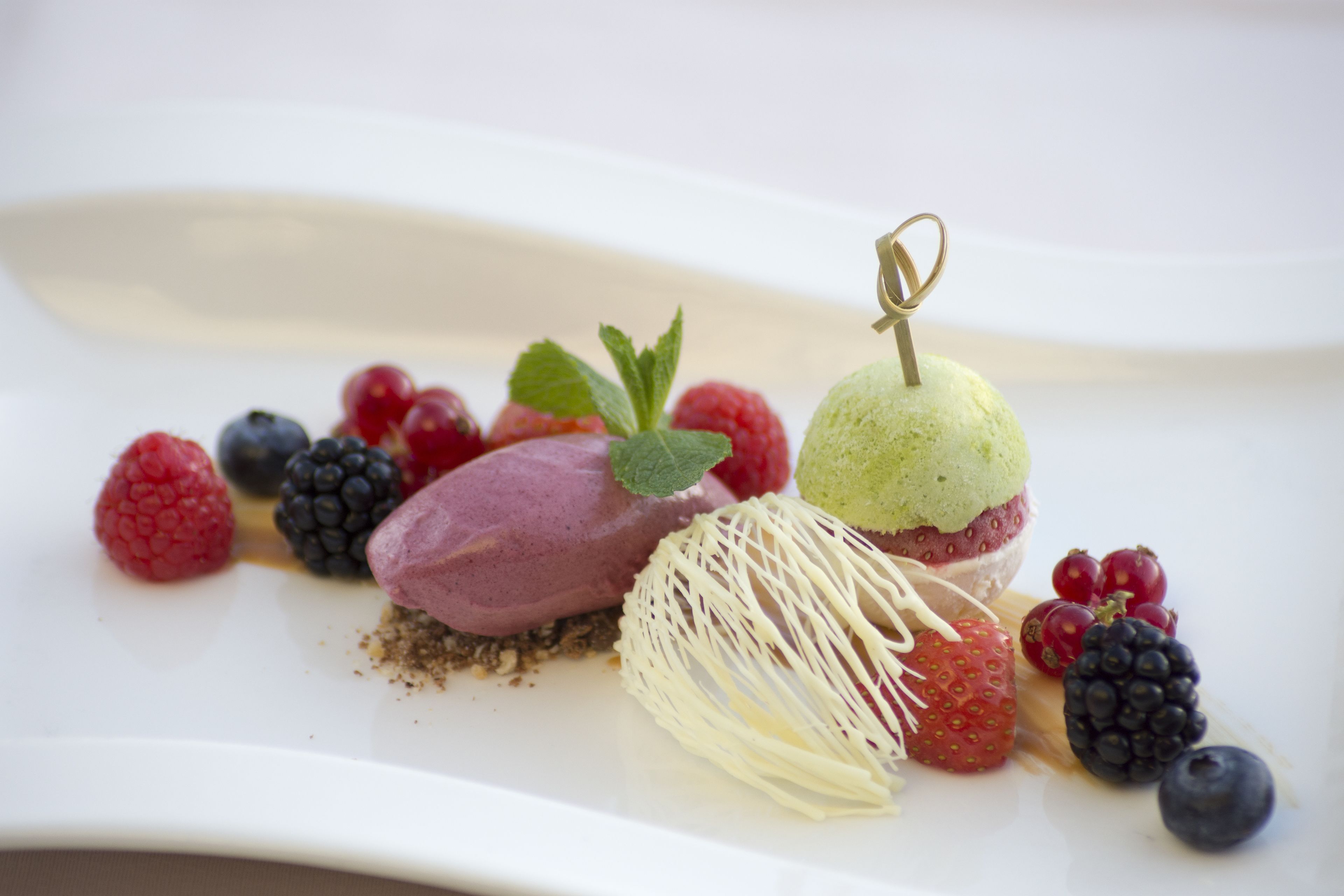 A dessert plate with various berries and a scoop of ice cream.
