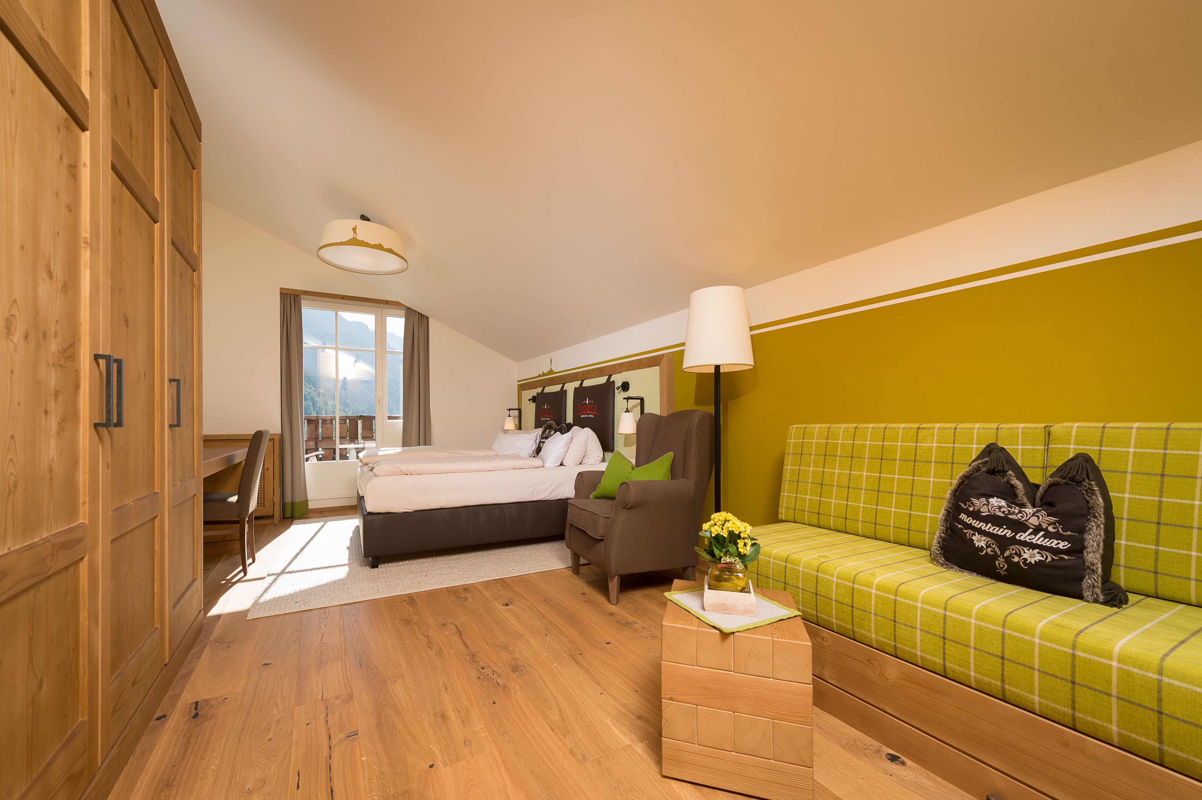 A bedroom with a bed, a chair, a sofa, and a lamp.