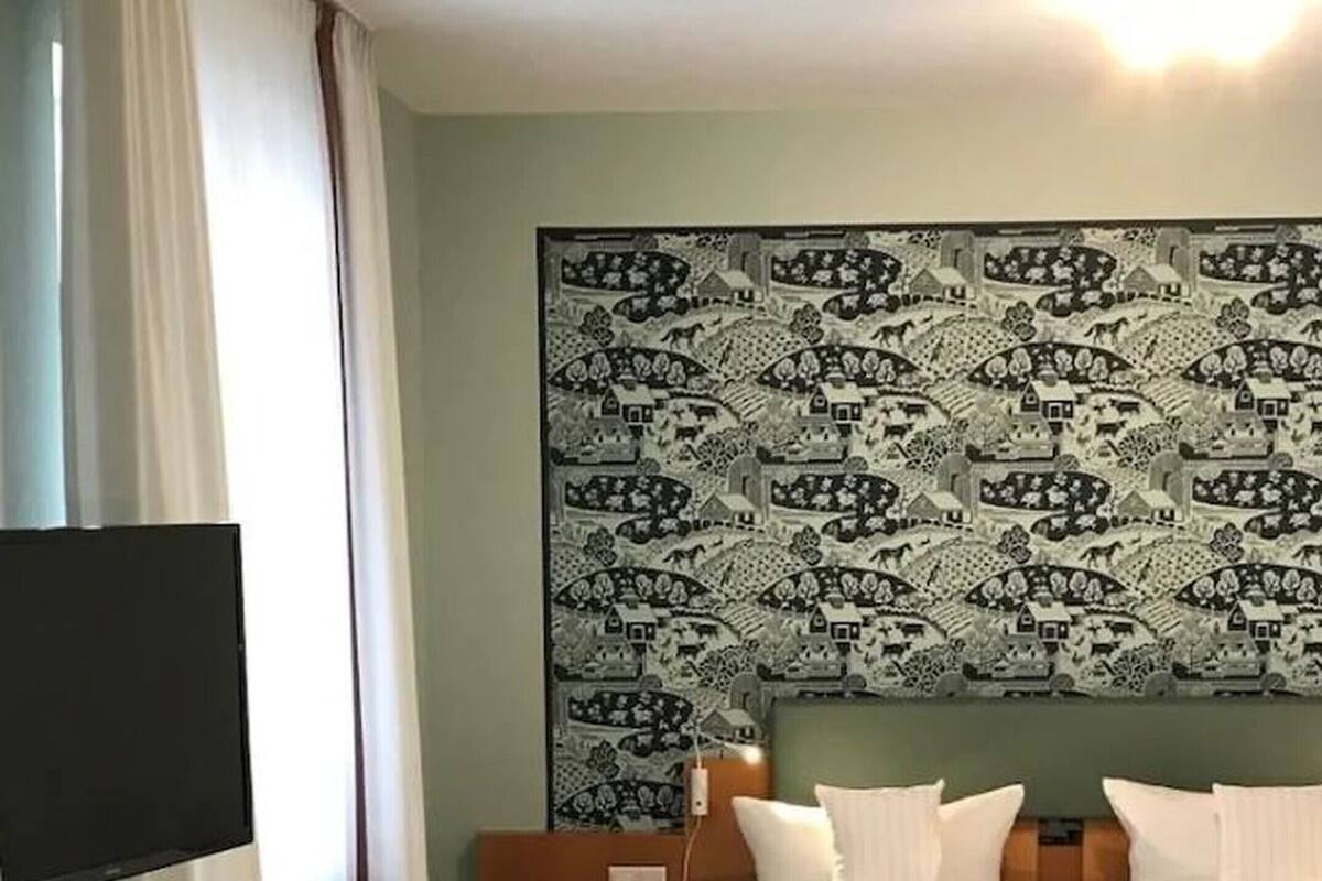 A hotel room with a bed, a TV, a desk, and a chair.