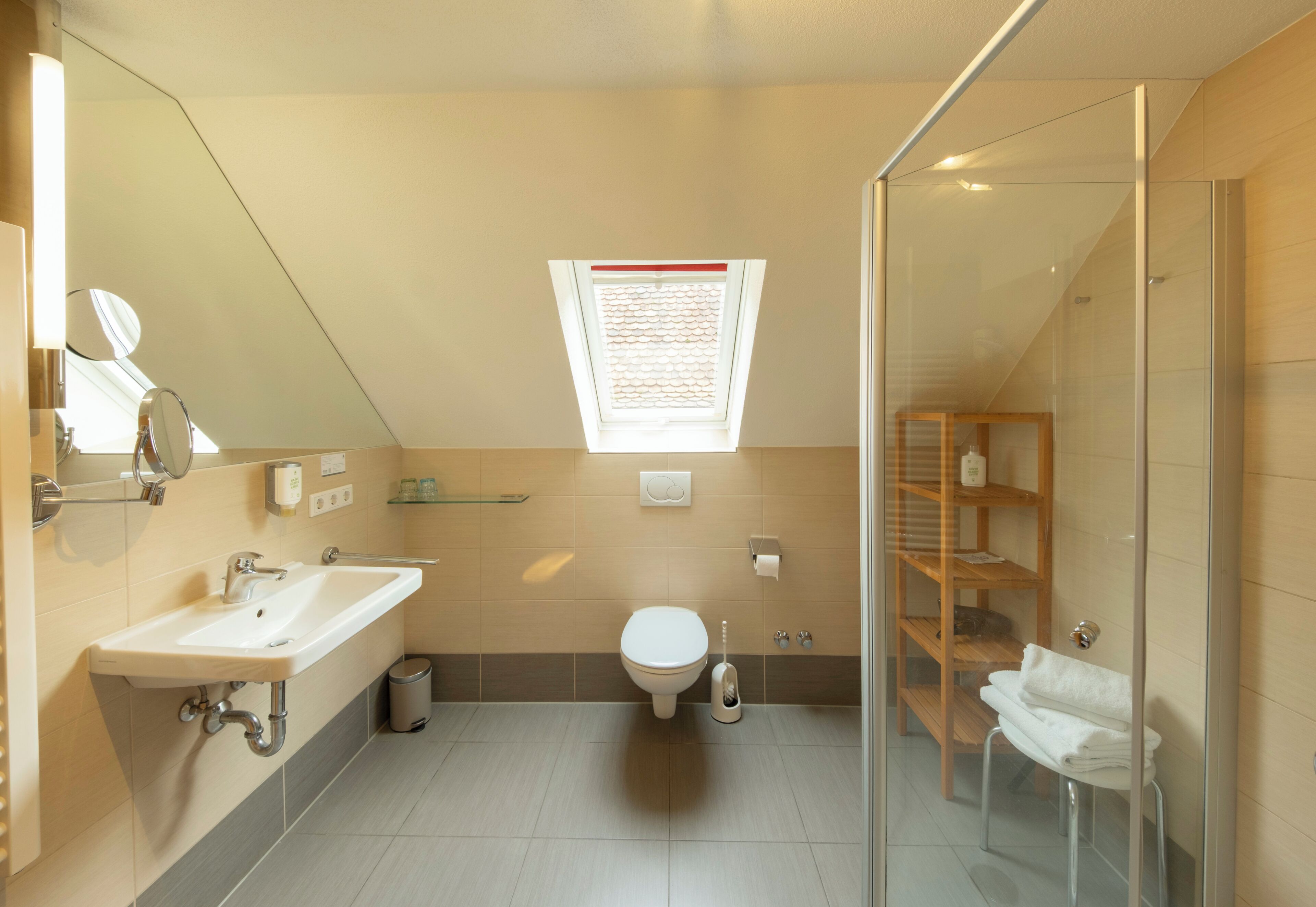 A modern bathroom with a skylight, a glass shower enclosure, and a built-in shelf.