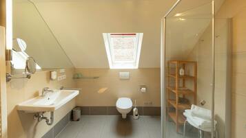 A modern bathroom with a skylight, a glass shower enclosure, and a built-in shelf.
