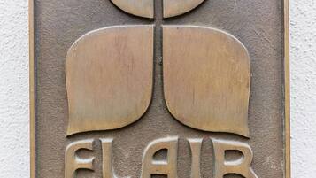 Une plaque métallique portant l’inscription « FLAIR HOTEL » et un logo stylisé.