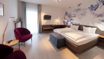 Quarto de hotel moderno com uma cama grande, uma escrivaninha, uma cadeira e uma televisão.