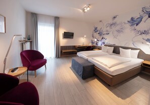 A modern hotel room with a large bed, a desk, a chair, and a TV. - Flair Hotel Zum Storchen (Bad Windsheim)