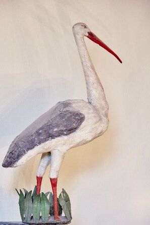 A sculpture of a bird with a long neck and red beak, standing on a base with green leaves. - Flair Hotel Zum Storchen (Bad Windsheim)