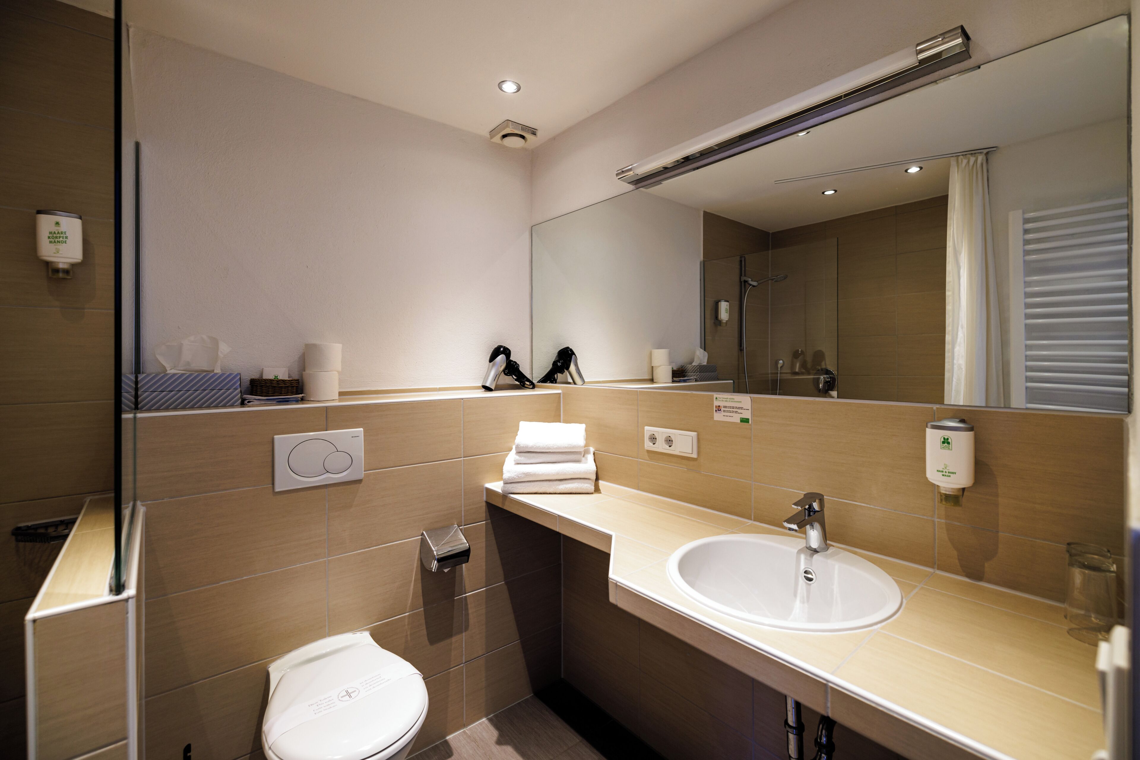 Un baño moderno con inodoro, lavamanos y ducha.