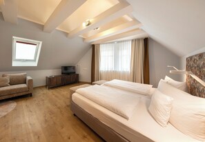 A bedroom with a large bed, a sofa, a TV, and a window with curtains. - Flair Hotel Zum Storchen (Bad Windsheim)
