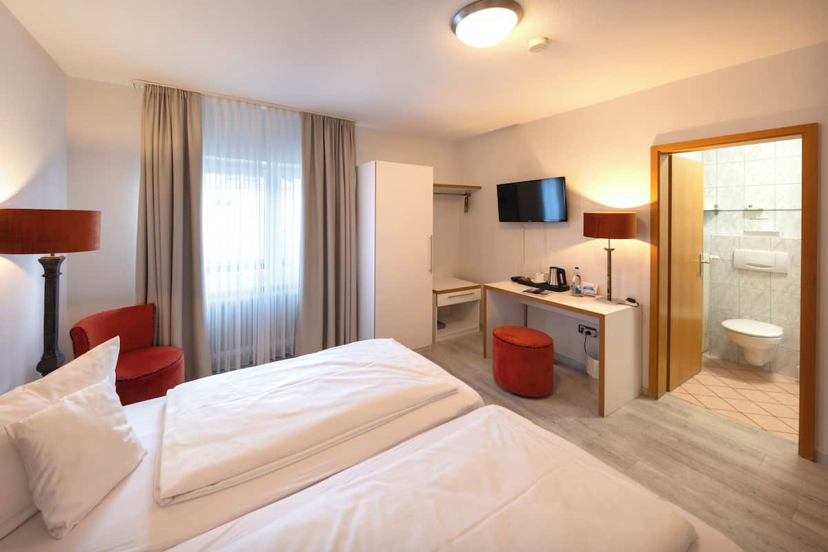 A hotel room with a bed, desk, chair, television, and bathroom.