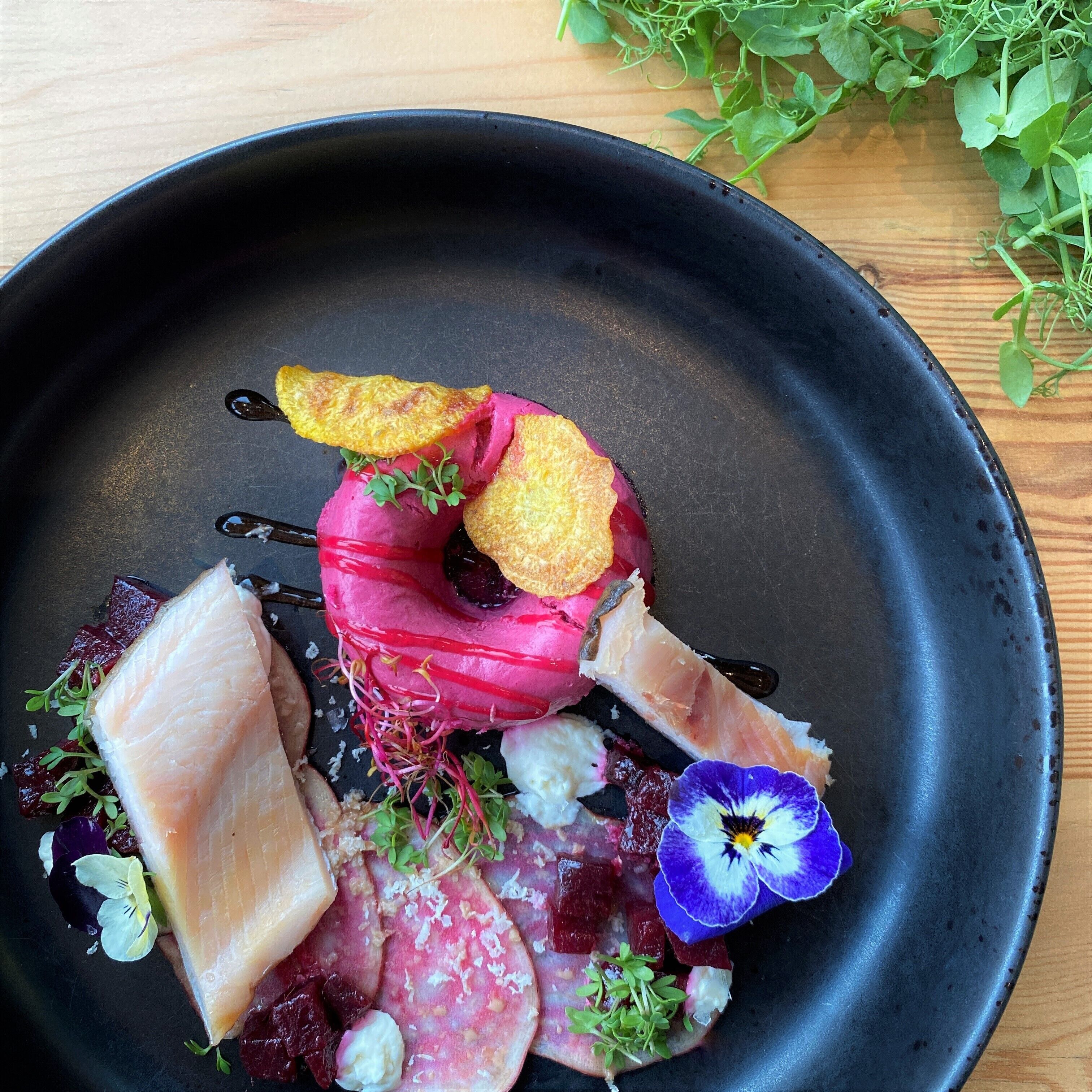 A black plate with various food items including fish, meat, and vegetables.