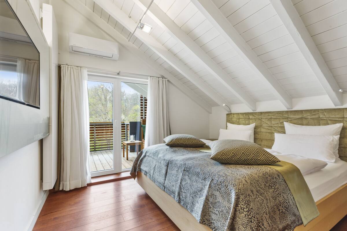 A bedroom with a large bed, a wooden headboard, and a sliding glass door leading to an outdoor area.