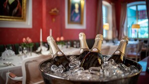 A dining area with a table set for a meal, a bucket of ice, and champagne bottles. - Romantik Hotel Landschloss Fasanerie (Zweibruecken)