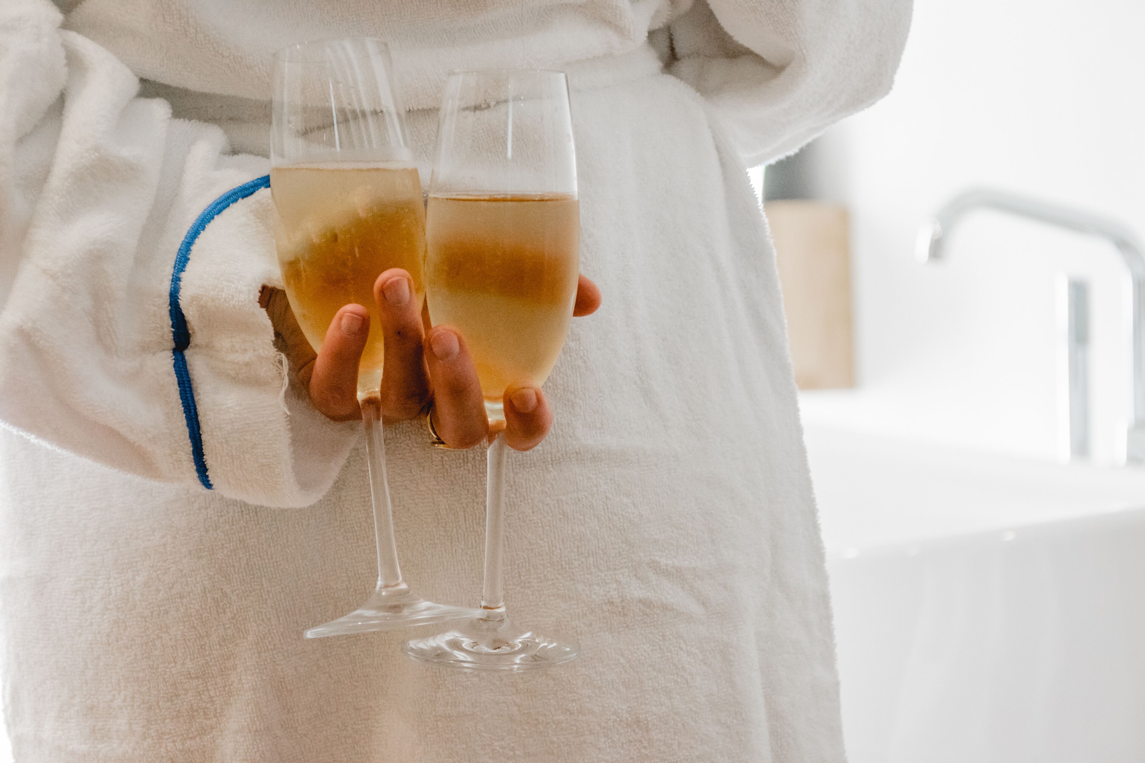 Une personne tenant deux verres contenant une boisson de couleur claire.