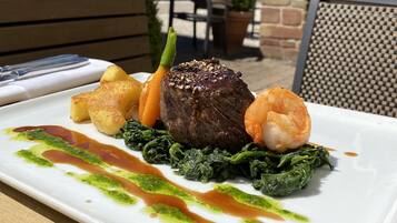 Plat amb entrecot, gambes i verdures, presentat sobre un plat blanc.