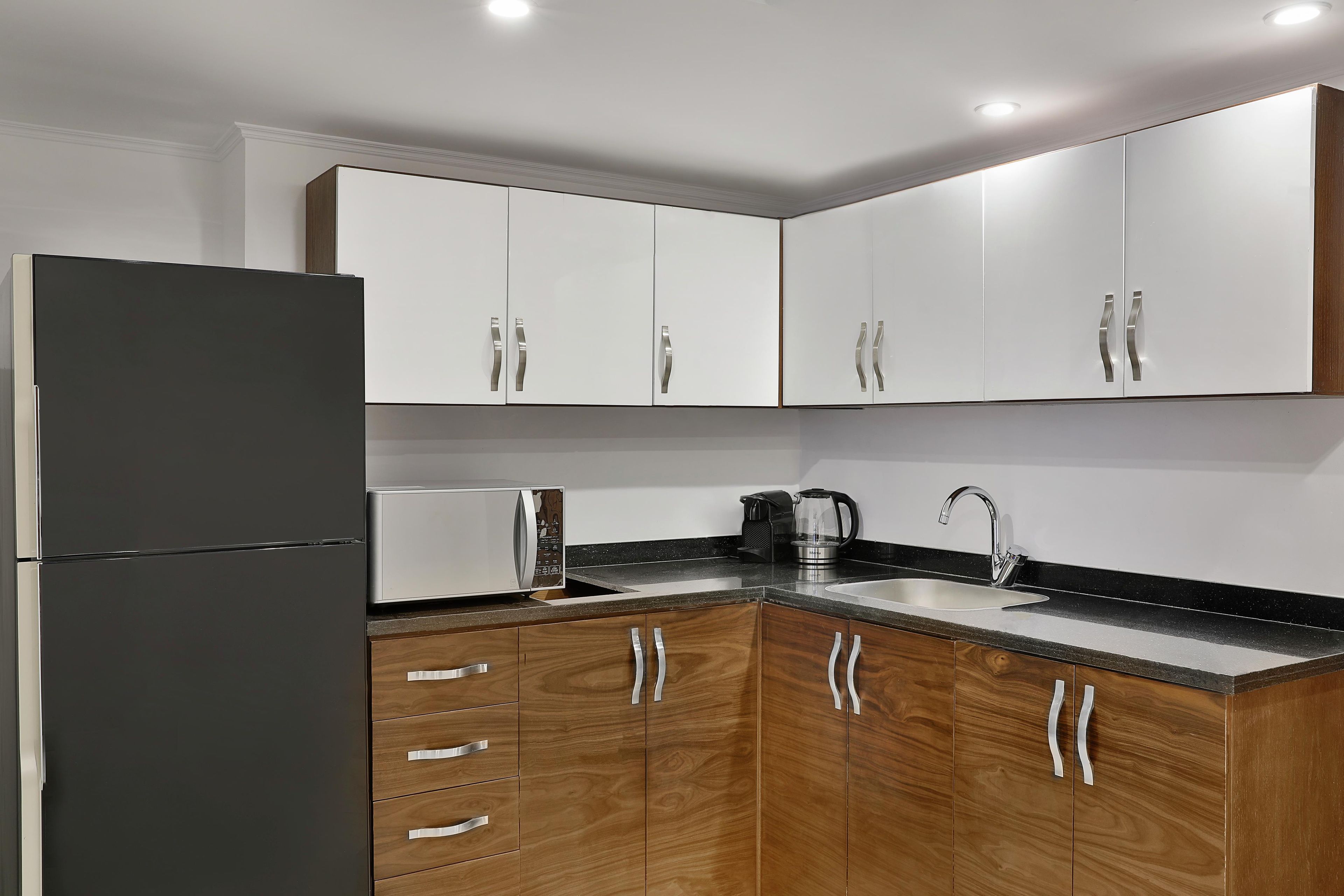 Una cocina moderna con refrigerador, microondas, cafetera y lavamanos.