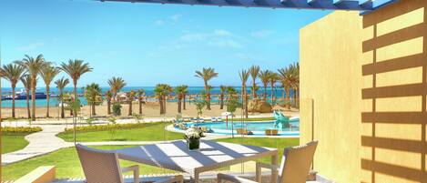 Un espace extérieur aménagé, abrité et doté de sièges, offrant une vue sur une piscine et une plage.