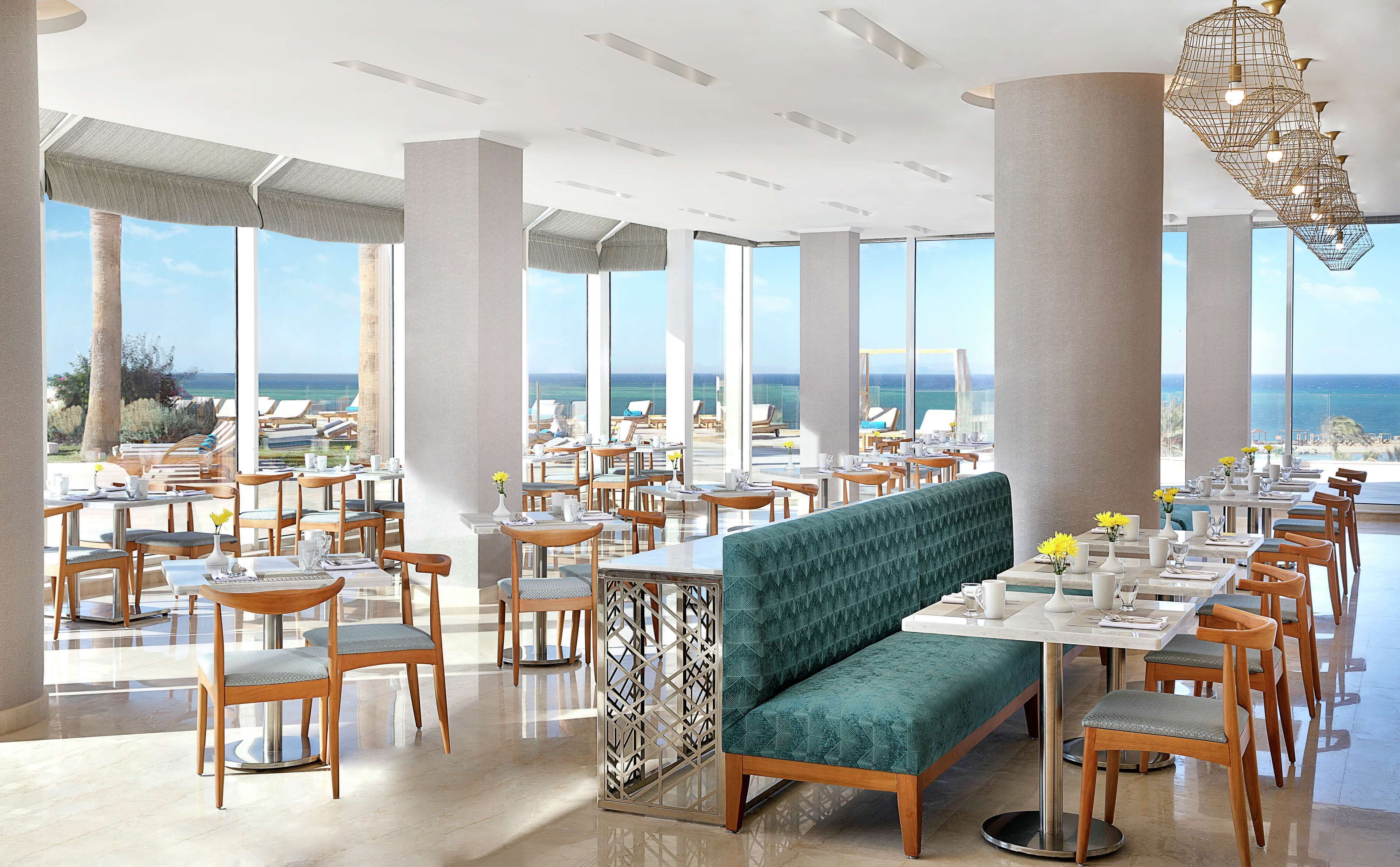 A spacious dining area with high ceilings, large windows, and a view of the ocean.
