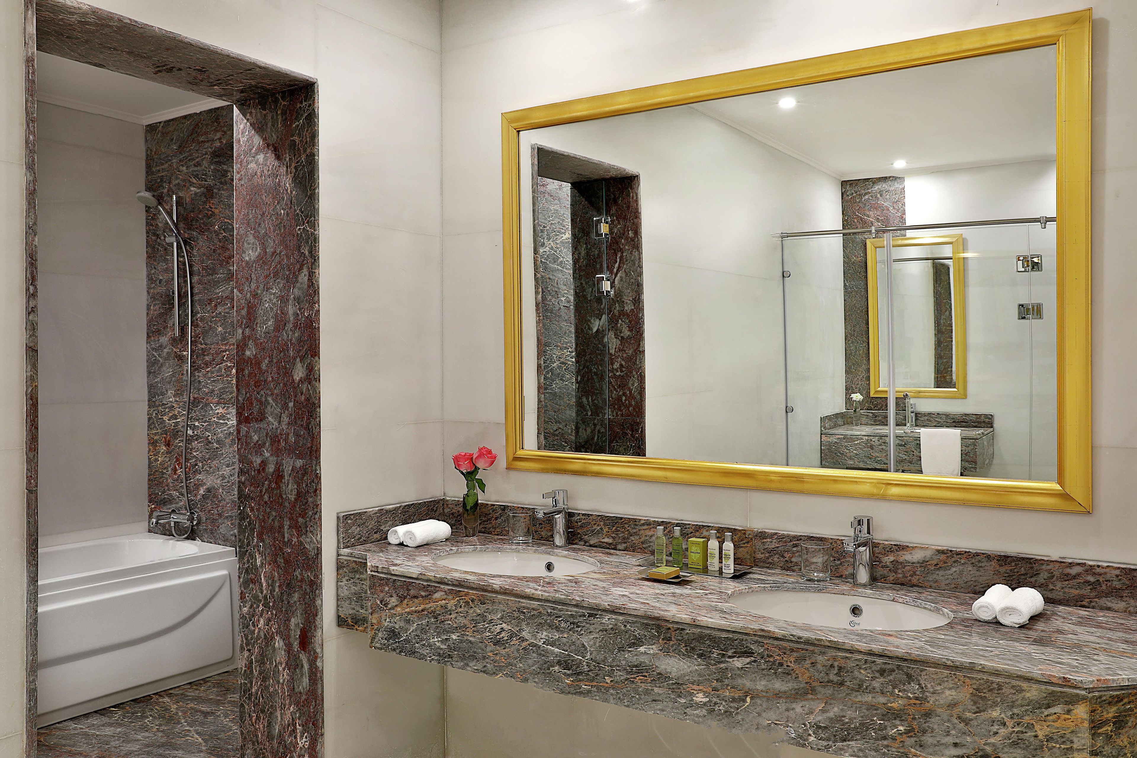 Un baño con tocador de mármol, un espejo grande y una zona de ducha.