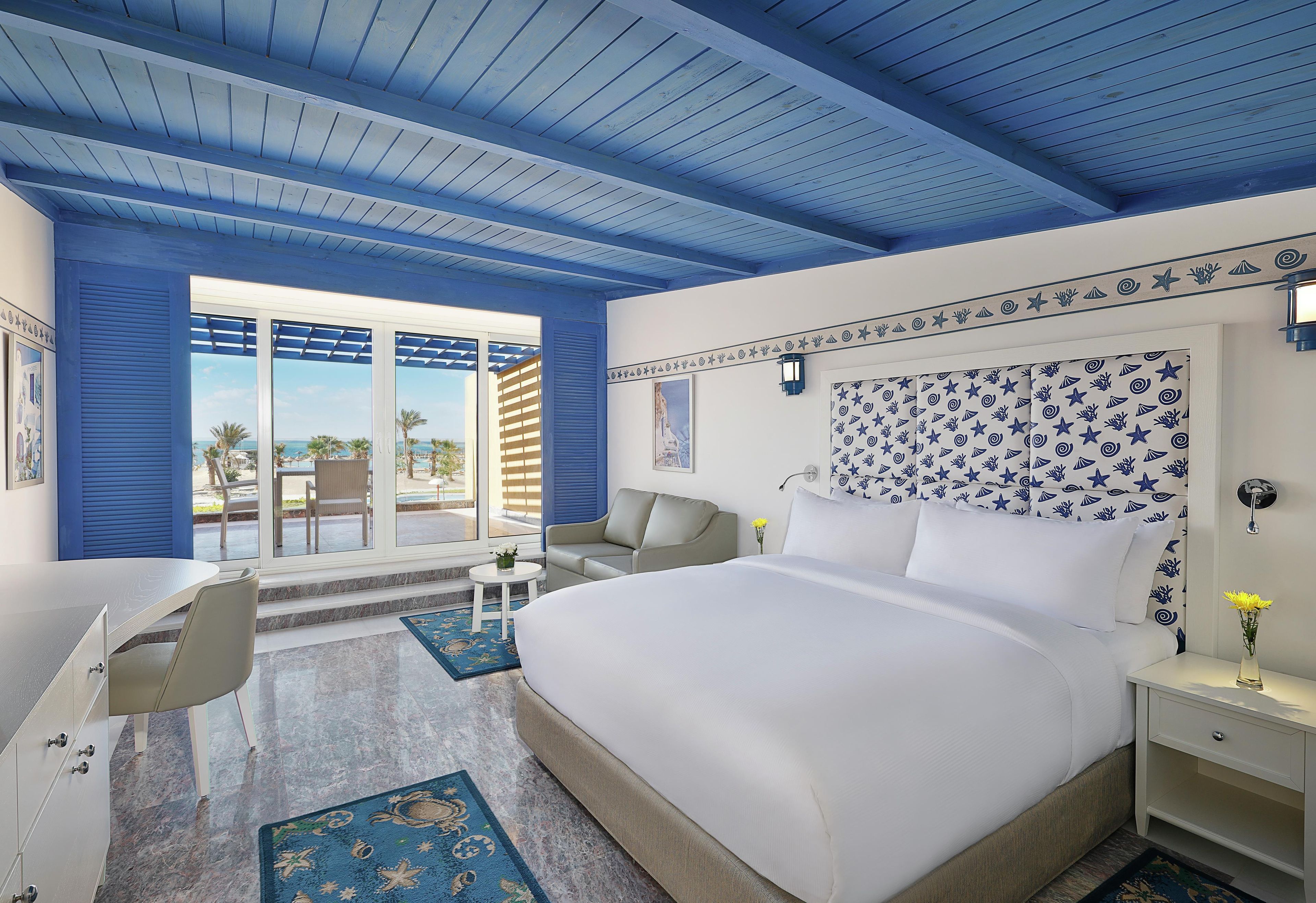 A hotel room with a large bed, a desk, and a view of the outdoors.