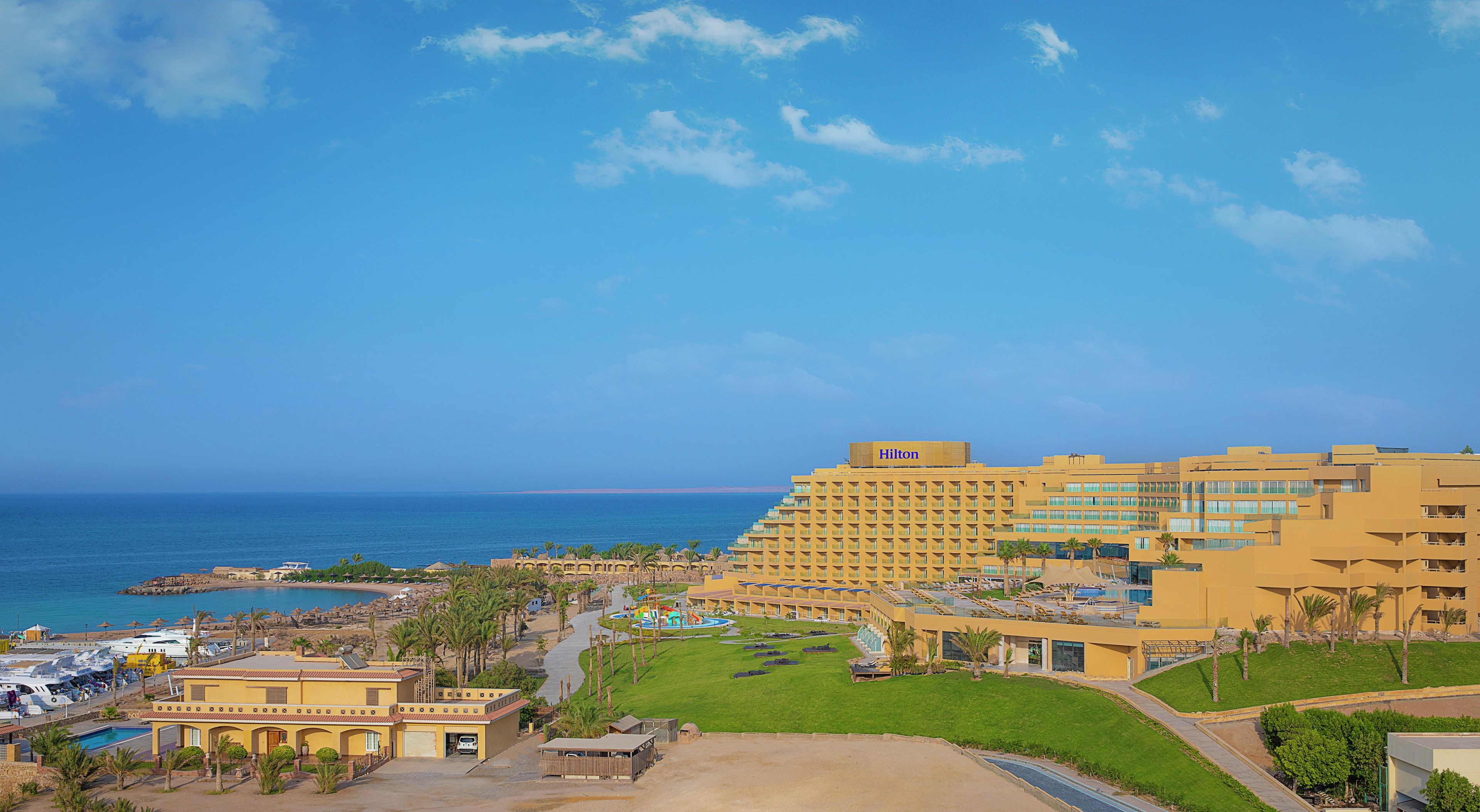 A hotel with multiple buildings, a pool area, and a view of the sea.