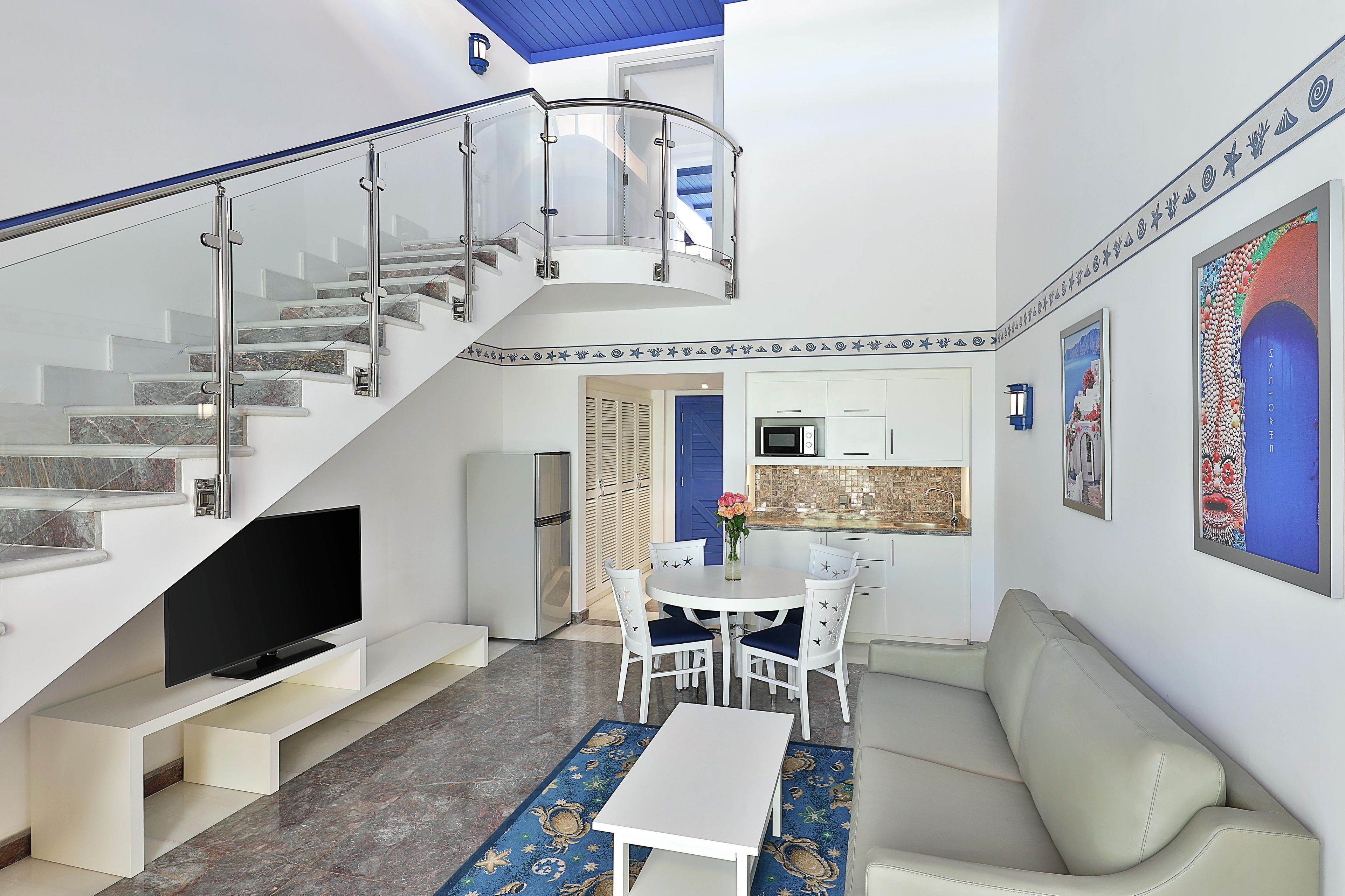Un interior moderno con escalera, televisor de pantalla plana, zona de comedor y cocina.