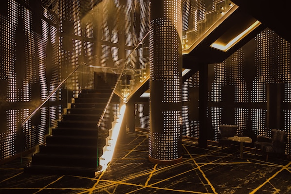 A modern interior with a staircase, seating area, and illuminated walls. - Hilton Hurghada Plaza (Hurghada)