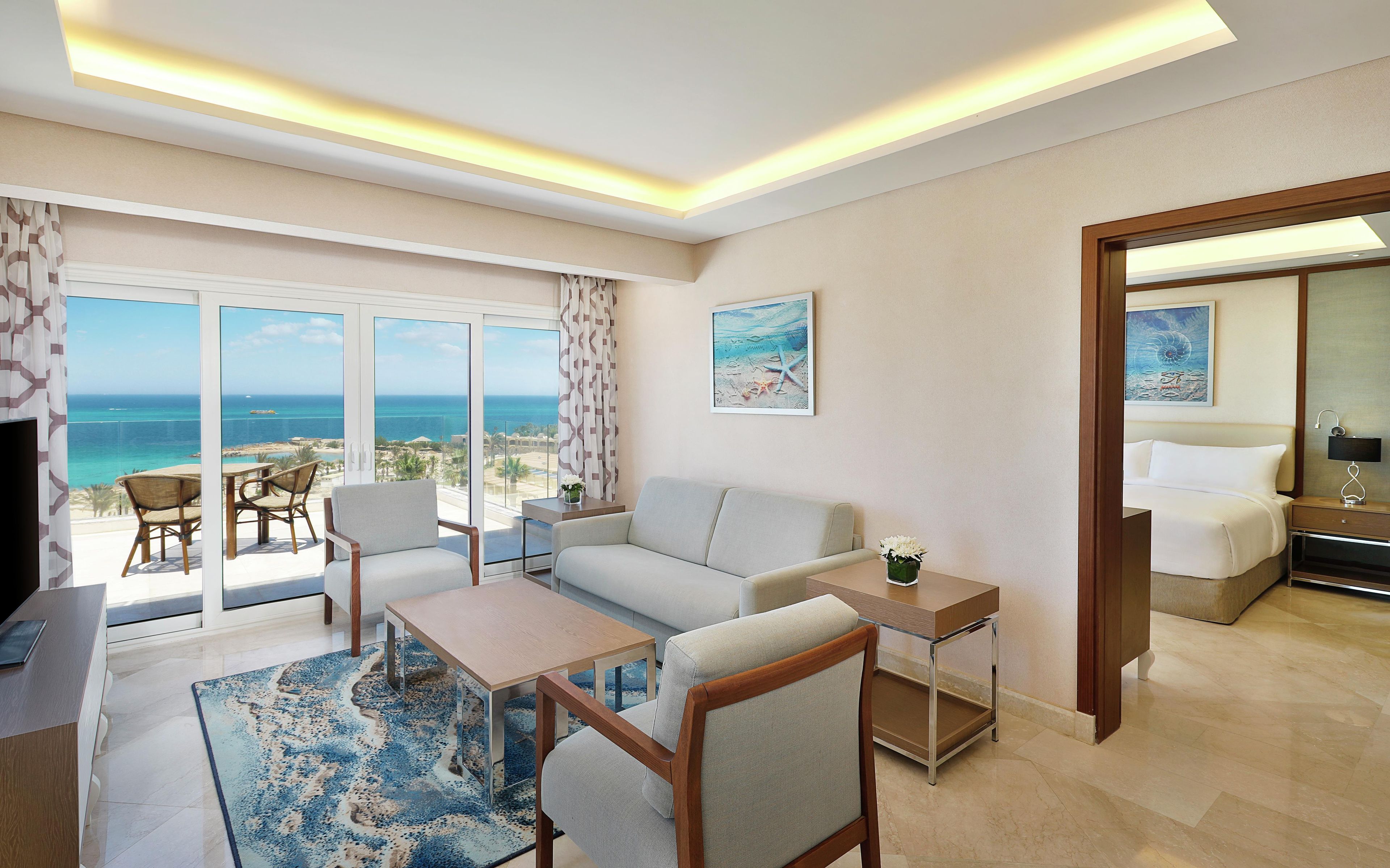 A hotel room with a balcony, a sofa, a table, and a bed.