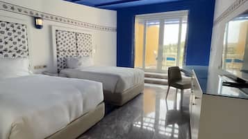 Habitación de hotel con dos camas, un escritorio y un ventanal grande.