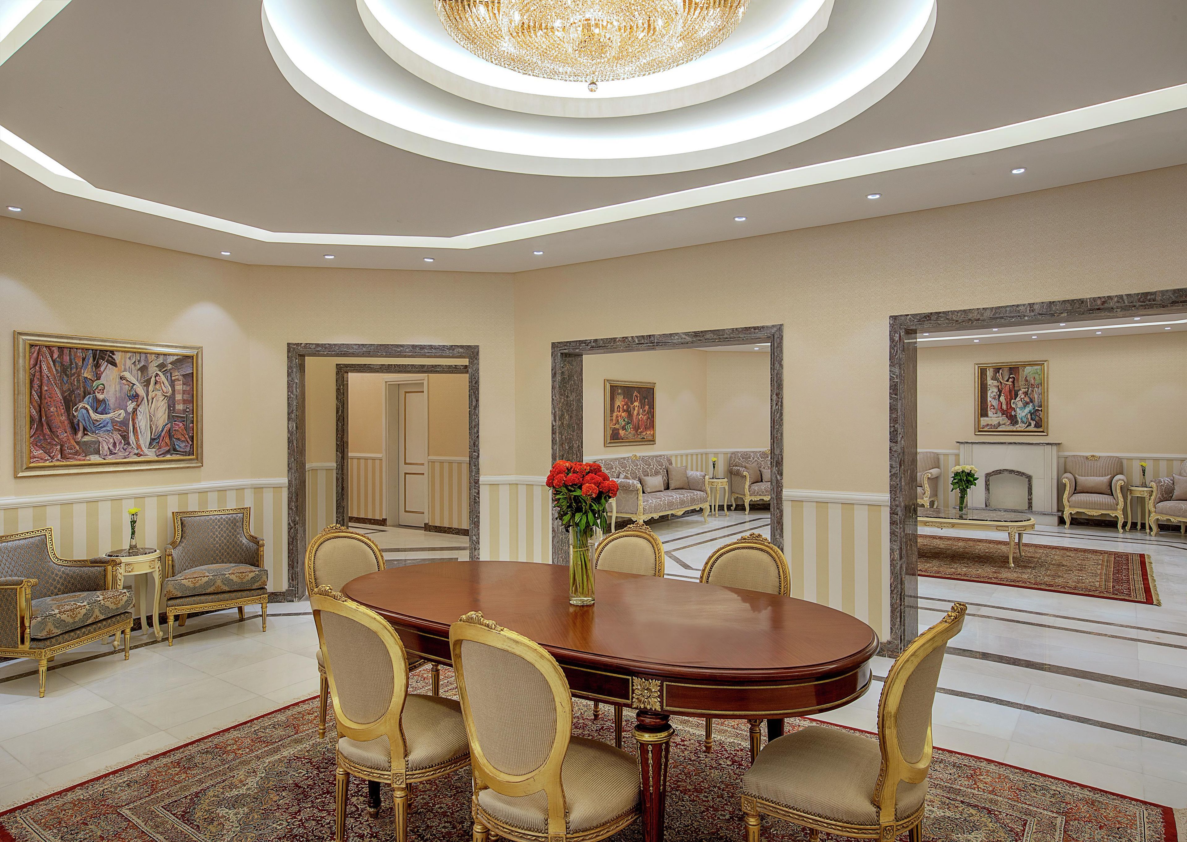 A formal dining room with a round table, chairs, and a chandelier.
